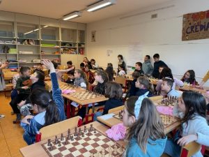 Bambini seduti in classe con scacchiere sui banchi