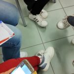 particolare di ragazzi e genitori al lavoro in cerchio con smartphone