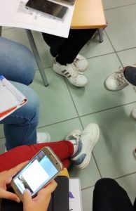 particolare di ragazzi e genitori al lavoro in cerchio con smartphone