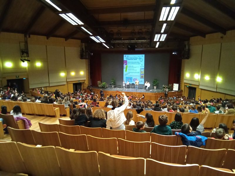panoramica auditorium con ragazzi che votano alzando i cartellini