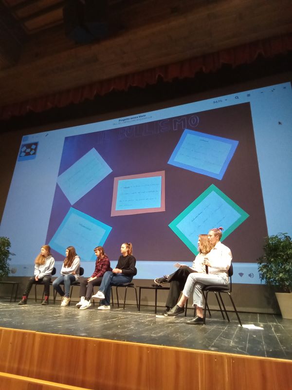 ragazzi sul palco, sullo sfondo è proiettato il cartellone creato dal nostro istituto