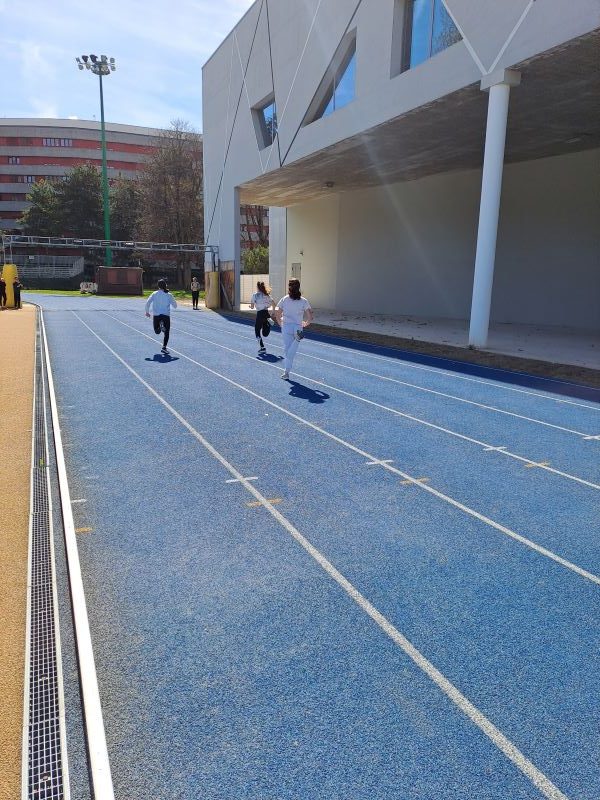 ragazzi di spalle corrono sulla pista di atletica