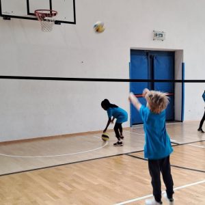 BAMBINI DI SPALLE CON MAGLIETTE AZZURRE GIOCANO NELLA PALESTRA DI GARDOLO
