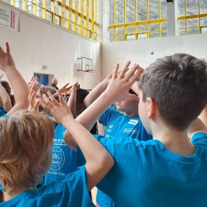 BAMBINI DI SPALLE CON MAGLIETTE AZZURRE GIOCANO NELLA PALESTRA DI GARDOLO