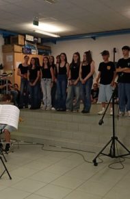studenti con maglietta nera con logo ic trento 4 cantano in aula di musica diretti dalla professoressa
