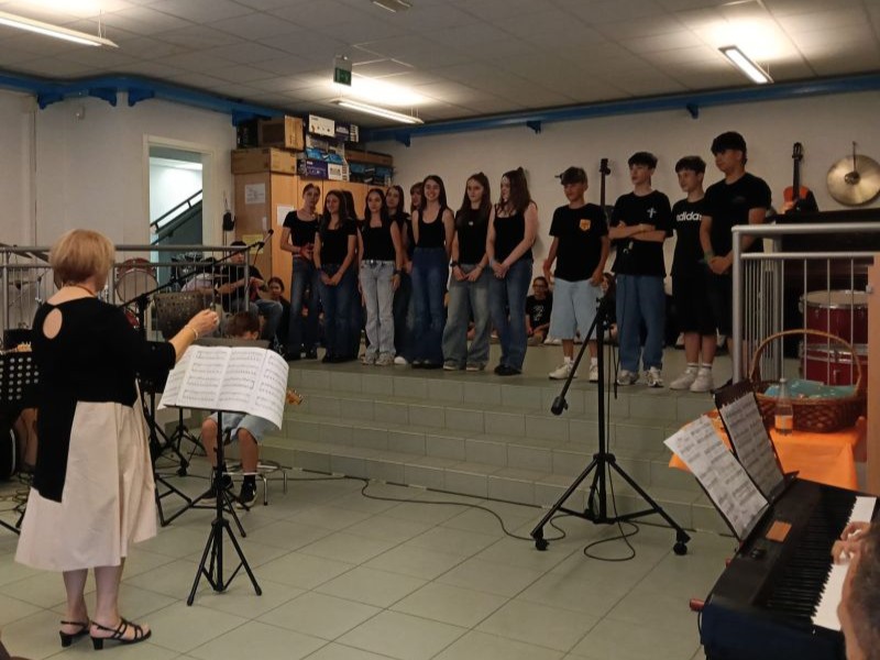 studenti con maglietta nera con logo ic trento 4 cantano in aula di musica diretti dalla professoressa
