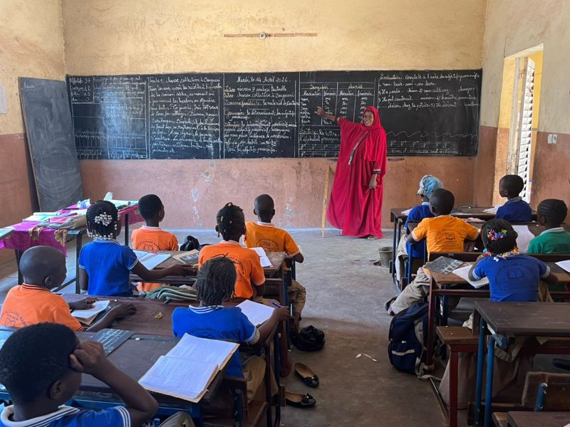alunni di una classe del mali seduti nella loro aula guardano l'insegnante che spiega alla lavagna