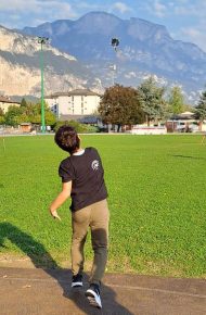 alunno con maglietta nera lancia il Vortex. Montagne e cielo azzurro sullo sfondo